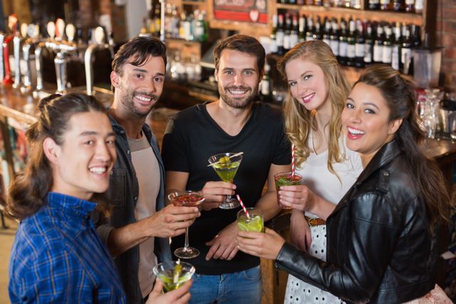 Portrait of smiling friends holding drinks while standing in bar - Download Free Stock Photos Pikwizard.com