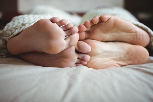 Couple showing their feet while lying on a bed  - Download Free Stock Photos Pikwizard.com