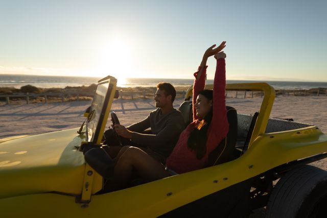 Happy caucasian couple driving in beach buggy by the sea at sunset, smiling and raising arms - Download Free Stock Photos Pikwizard.com