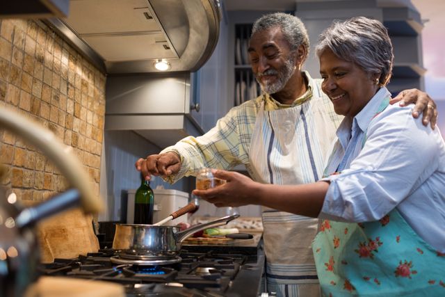 Smiling senior couple preparing food in kitchen - Download Free Stock Photos Pikwizard.com