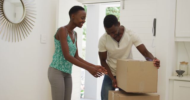 Happy african american couple stacking packing boxes in house and embracing. moving into a new home.