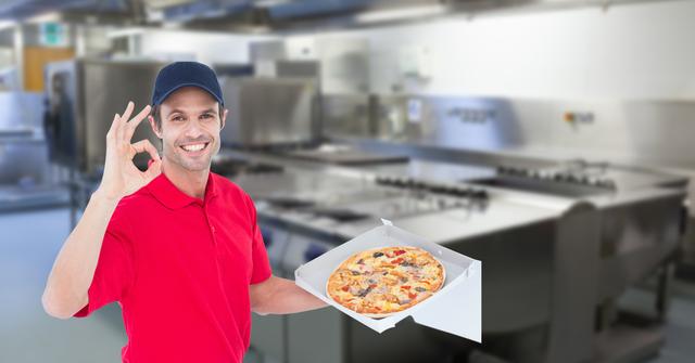 Delivery man showing OK gesture while holding pizza in kitchen - Download Free Stock Photos Pikwizard.com