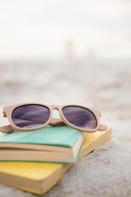Sunglasses and books on sand- Download Free Stock Photos Pikwizard.com