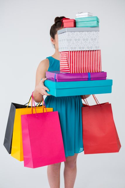 Woman carrying stack of gift boxes and shopping bags - Download Free Stock Photos Pikwizard.com