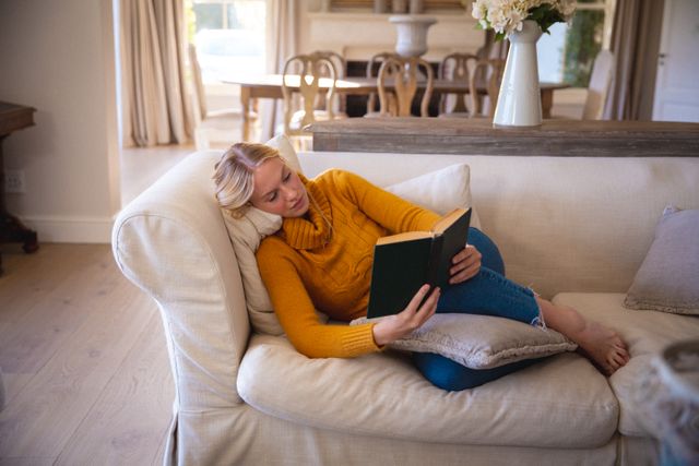 Caucasian female lying on couch, taking rest, reading book - Download Free Stock Photos Pikwizard.com