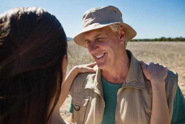 Smiling man looking at woman on field during sunny day