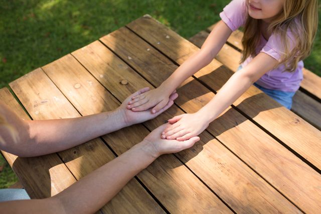Mother and daughter holding hands on picnic table - Download Free Stock Photos Pikwizard.com