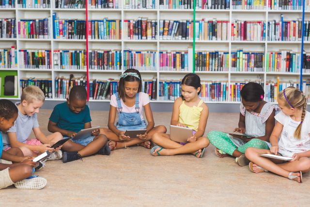 School kids sitting on floor using digital tablet in library - Download Free Stock Photos Pikwizard.com