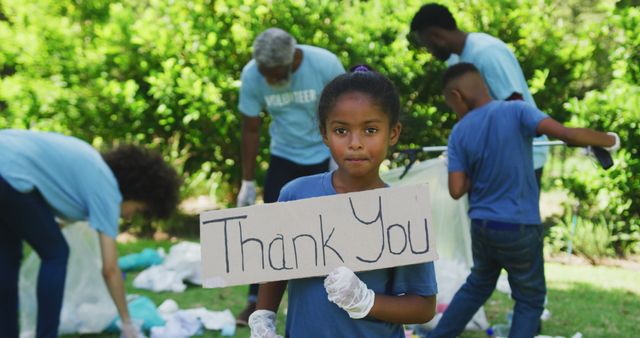 Smiling biracial granddaughter holding thank you sign, clearing up trash outdoors with family - Download Free Stock Photos Pikwizard.com