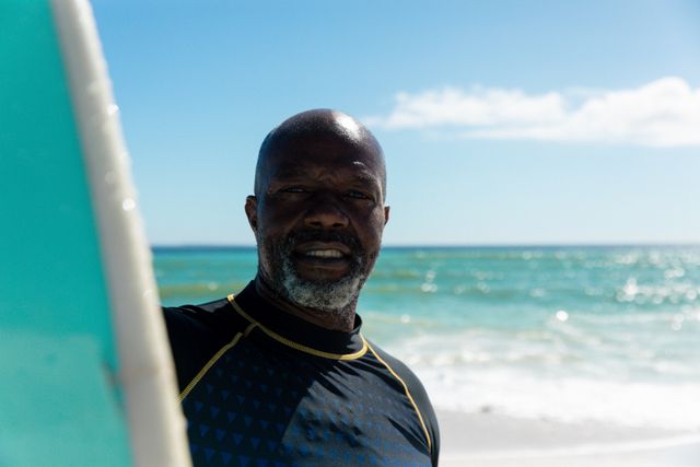 Portrait of african american bald retired senior man standing with surfboard at beach against sky - Download Free Stock Photos Pikwizard.com