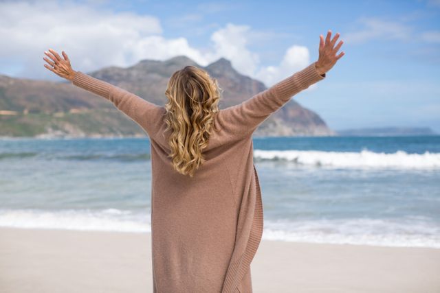 Mature woman with arms outstretched standing on the beach - Download Free Stock Photos Pikwizard.com