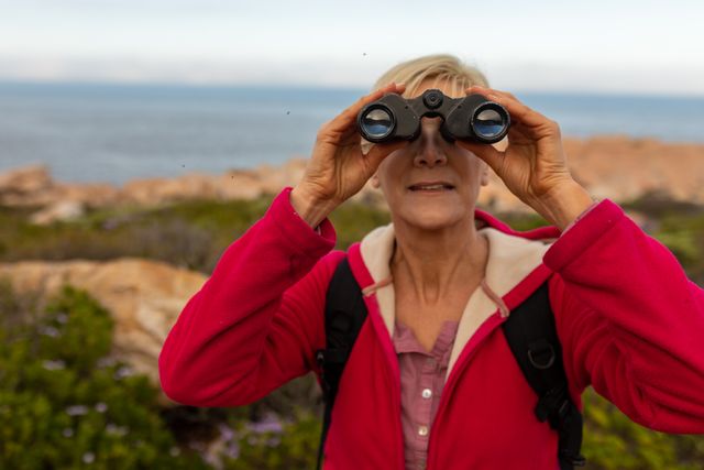 Caucasian hiker senior woman using binoculars while trekking in the mountains - Download Free Stock Photos Pikwizard.com