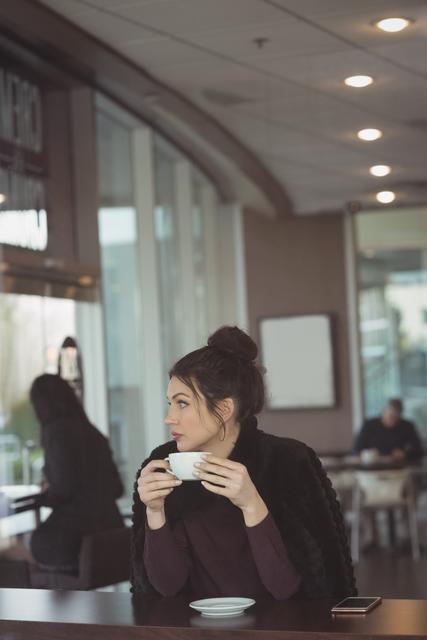 Thoughtful female executive having coffee in office cafeteria