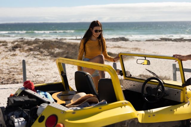 Smiling caucasian woman climbing into beach buggy on sunny beach by the sea - Download Free Stock Photos Pikwizard.com