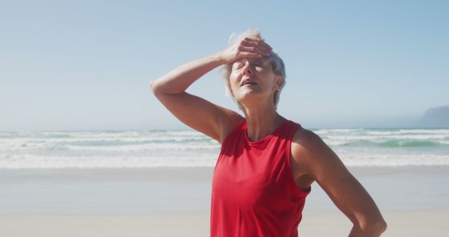 Senior caucasian woman wearing sports clothes and stretching at beach. Retirement, free time, healthy and active lifestyle.