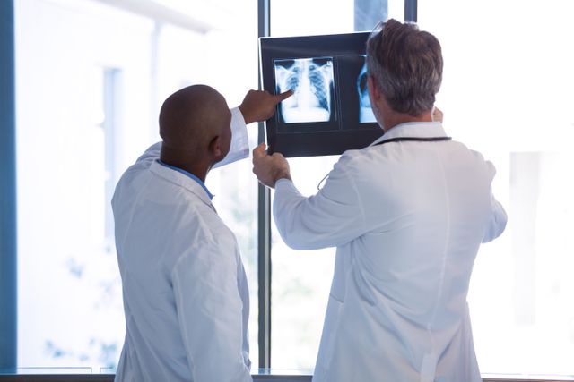 Doctors having discussion on x-ray report in corridor - Download Free Stock Photos Pikwizard.com