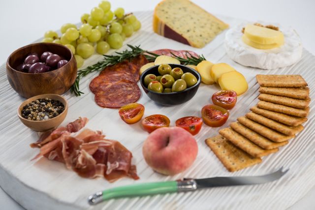 Variety of cheese with grapes, olives, salami, crackers and knife - Download Free Stock Photos Pikwizard.com