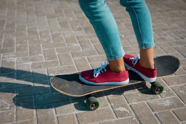 Low section of mixed race woman wearing trainers standing on skateboard - Download Free Stock Photos Pikwizard.com