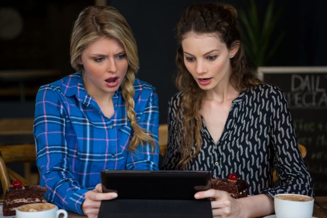 Shocked women using digital tablet in coffee shop - Download Free Stock Photos Pikwizard.com