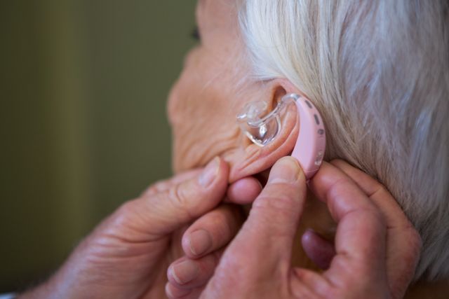 Doctor inserting hearing aid in senior patient ear - Download Free Stock Photos Pikwizard.com