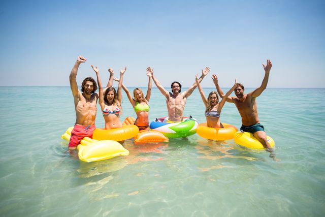 Friends enjoying on inflatable rings and pool rafts in sea - Download Free Stock Photos Pikwizard.com