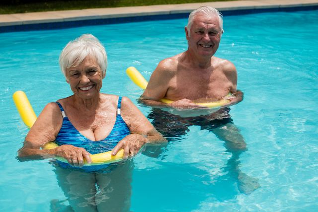 Senior couple swimming in the pool with inflatable tubes - Download Free Stock Photos Pikwizard.com