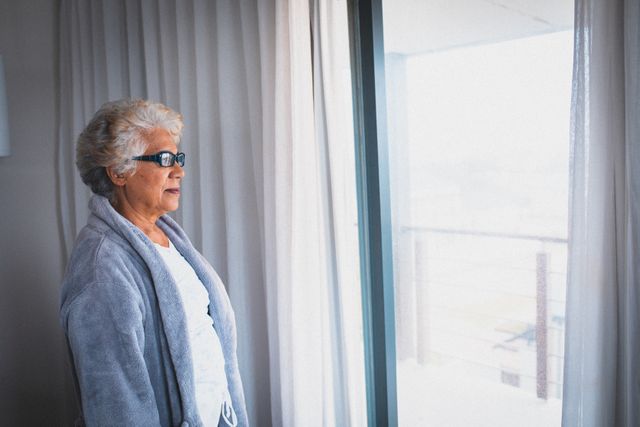 African american senior woman looking out of the window at home. retirement senior lifestyle living in quarantine lockdown concept