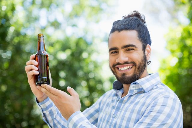 Man holding beer bottle in the park - Download Free Stock Photos Pikwizard.com
