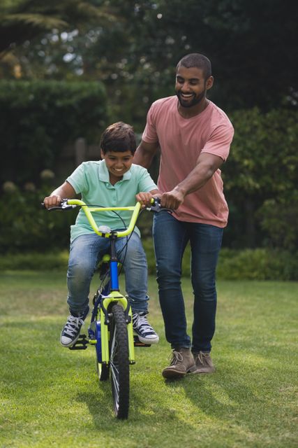 Father assisting son while riding bicycle - Download Free Stock Photos Pikwizard.com