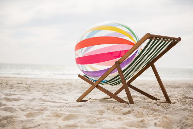 Striped beach ball kept on empty beach chair - Download Free Stock Photos Pikwizard.com