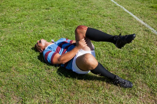 Full length of rugby player with injured knee lying on field - Download Free Stock Photos Pikwizard.com