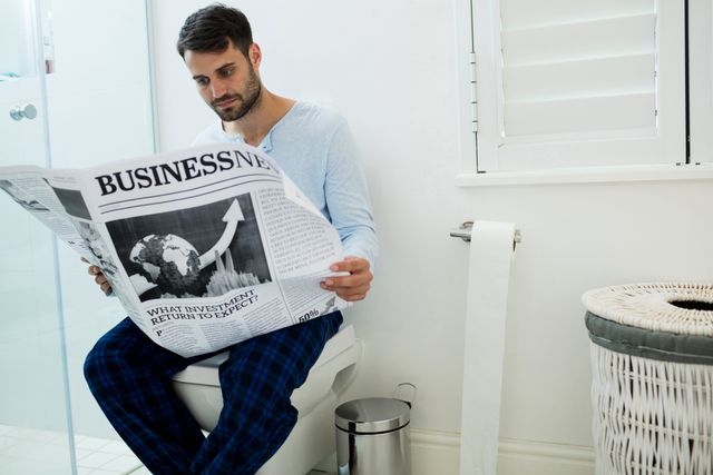 Man sitting on toilet seat reading a newspaper - Download Free Stock Photos Pikwizard.com
