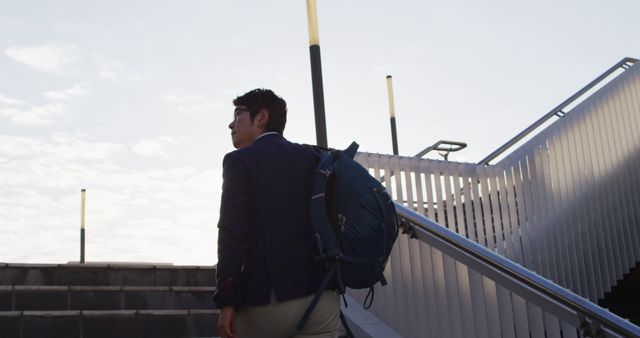 Asian man with backpack climbing up the stairs at corporate park. business and lifestyle concept
