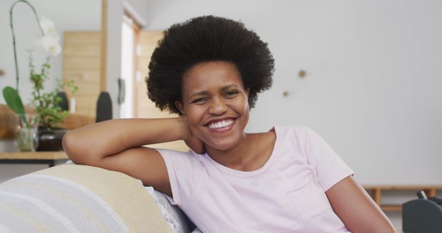 Portrait of happy african american woman sitting on sofa looking at camera. domestic lifestyle, spending free time at home.