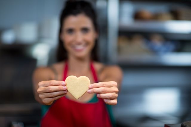 Close-up of female staff showing heart shape cookie at counter - Download Free Stock Photos Pikwizard.com