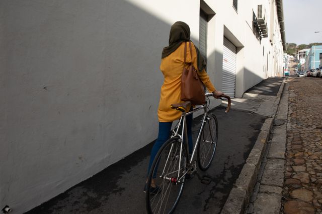 Rear view of woman in hijab walking with her bicycle - Download Free Stock Photos Pikwizard.com