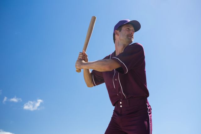 Low angle view of young baseball player holding bat against blue sky - Download Free Stock Photos Pikwizard.com