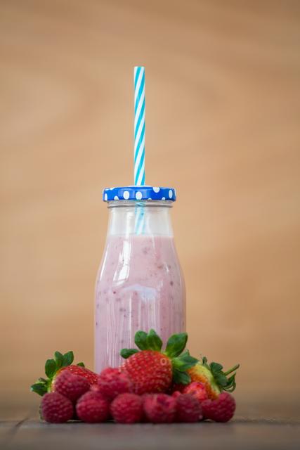 Strawberry, raspberry and bottle smoothie on wooden board