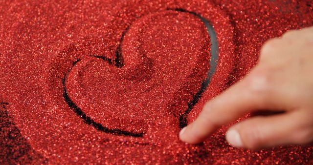 Person drawing shape of heart on red glitter - Download Free Stock Photos Pikwizard.com