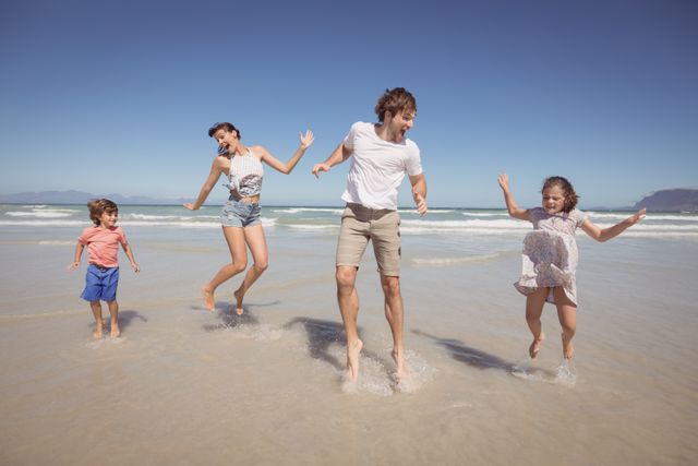 Cheerful family jumping on shore at beach - Download Free Stock Photos Pikwizard.com