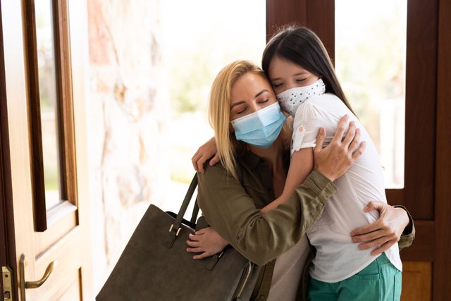 Caucasian mother and her daughter wearing facemasks hugging inside their house - Download Free Stock Photos Pikwizard.com