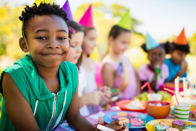 Close up of cute boy smiling in front of other children during a birthday party - Download Free Stock Photos Pikwizard.com