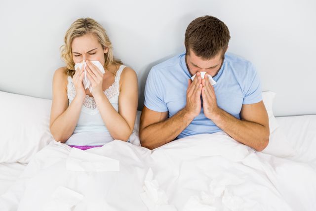 Couple covering nose while sneezing on bed - Download Free Stock Photos Pikwizard.com
