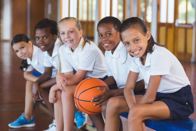 Portrait of school kids sitting in basketball court - Download Free Stock Photos Pikwizard.com