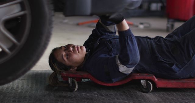 Female mechanic lying and working under car at a car service station. automobile repair service