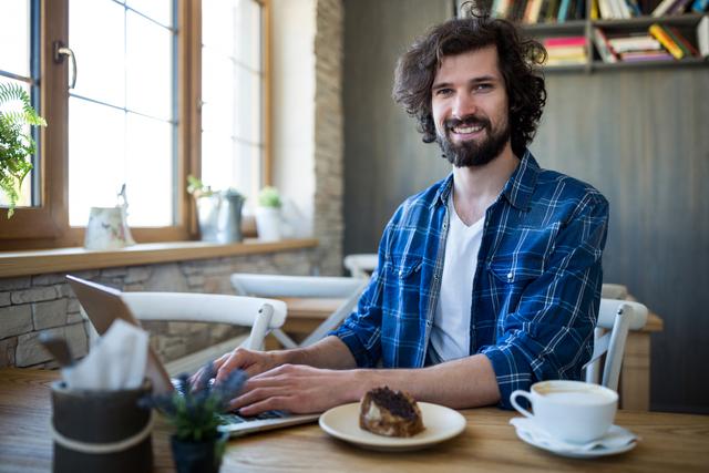 Smiling man using laptop in coffee shop - Download Free Stock Photos Pikwizard.com