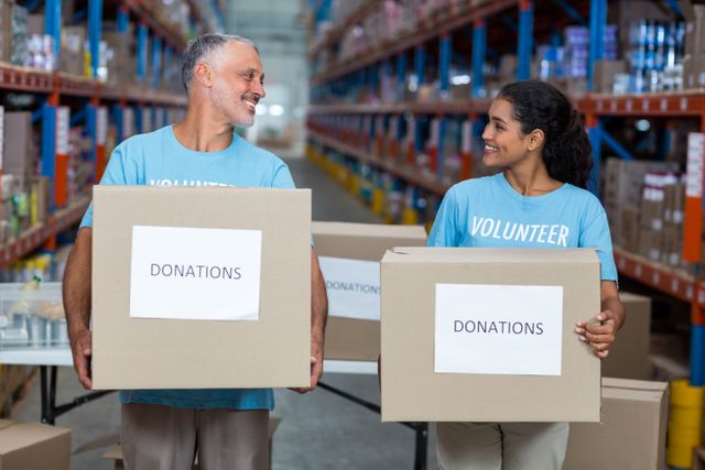 Happy volunteers are holding donations boxes and looking each other - Download Free Stock Photos Pikwizard.com