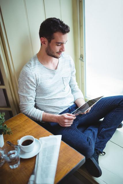 Man sitting at table in cafÃ© and using digital tablet