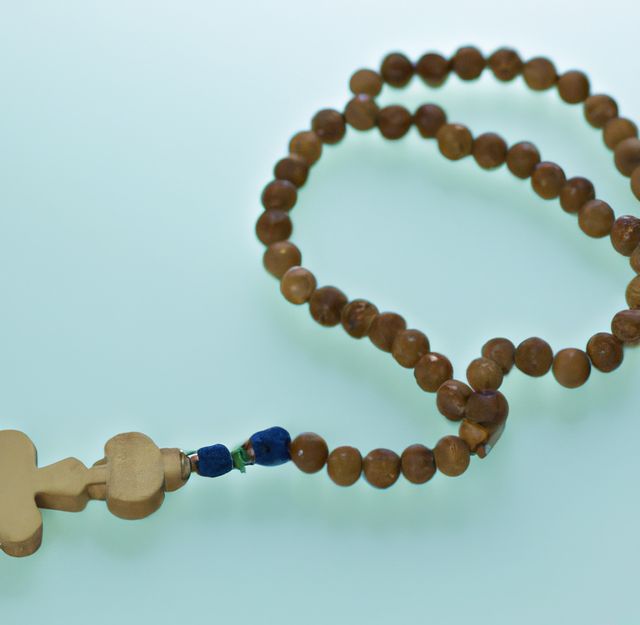 Close up of wooden rosary with cross on white background. Religion, faith and prayer concept.
