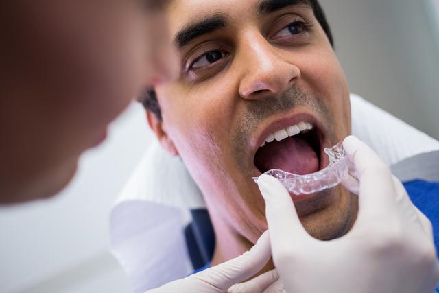 Dentist assisting a patient to wear invisible braces - Download Free Stock Photos Pikwizard.com